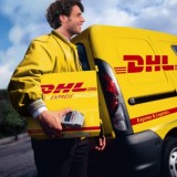 DHL staff member in front of branded truck with package in tow