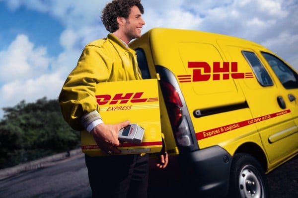DHL staff member in front of branded truck with package in tow