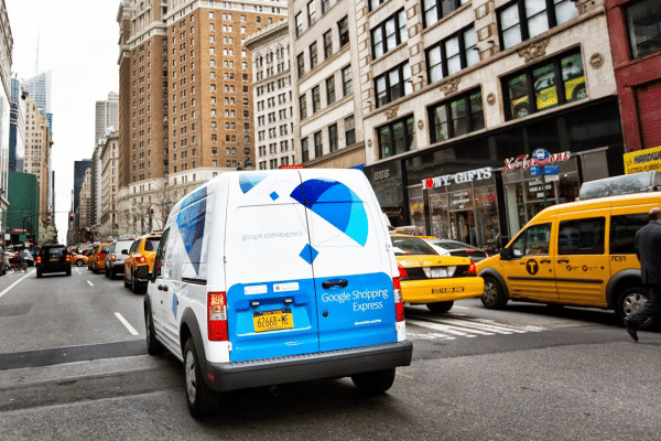 white and blue branded Google Package truck driving through urban setting
