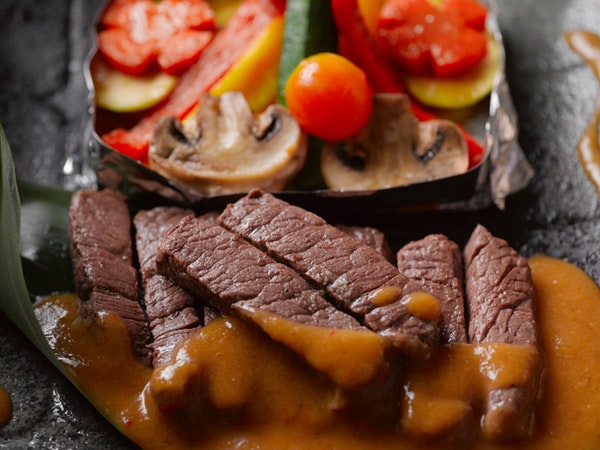 Steak with gravy near vegetables